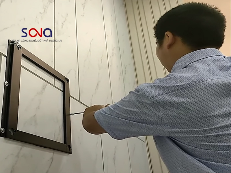 Kỹ thuật viên tiến hành bắt vít cố định khung treo màn hình quảng cáo lên tường ốp đá vân mây